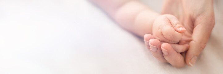 a little baby hand in mothers palm on white background, banner with free copy space