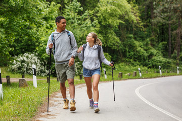 Wall Mural - young couple hiking in nature. they're walking by the old country road.