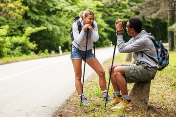 Wall Mural - young couple hiking in nature.they sitting and resting by the old country road.