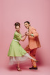 © LIGHTFIELD STUDIOS - elegant dancers holding hands while dancing boogie-woogie on pink background