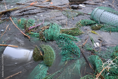 Plastic and microplastic waste and garbage floating in the water with fishing net. Ocean and sea plastic pollution