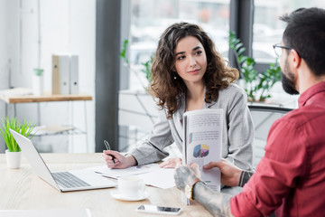 Wall Mural - account manager sitting at table and talking with colleague