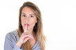 © OceanProd - Young blonde woman over isolated white background doing silence gesture shh aside copy space