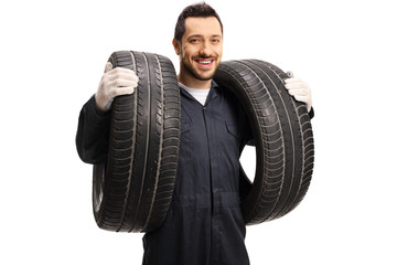 An auto mechanic carrying two car tires