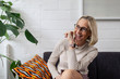 © Westend61 - Happy mature businesswoman with smartwatch sitting on couch in office lounge