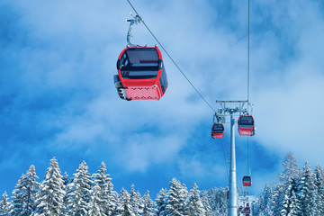 Wall Mural - Red Cable cars in Zillertal Arena ski resort in Tyrol in Mayrhofen in Austria in winter Alps. Chair lifts in Alpine mountains with white snow and blue sky. Downhill fun at Austrian snowy slopes.