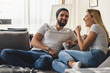 Young hipster couple sitting on sofa at home talking and drinking coffee
