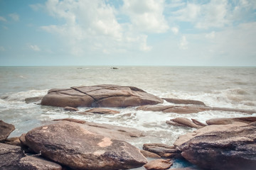 Waves are bumping rocks, Landscape of sea and stones on the beach with blue sky and clouds on background.