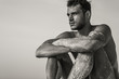 © PKpix - Sexy topless male model relaxed sitting on the beach.