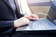 © suraphop - Cropped shot view of young businesswoman using laptop and smart phone  in a car.
