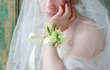 Bride wearing wrist corsage made of rose and eustoma flowers.