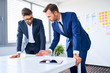 © baranq - Two businessmen discussing in office standing by the table