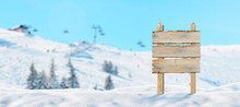 Blank, Wooden Road Sign On Snowy Mountain, Ski Resort. Ski Lift And Slopes In Background