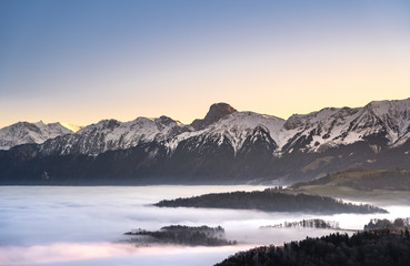Wall Mural - swiss mountain range in switzerland while the valley is covered in fog during sunset, super warm lig