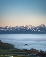 Wall Mural - swiss mountain range in switzerland while the valley is covered in fog during sunset, super warm lig