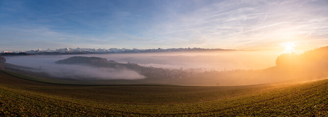 Wall Mural - swiss mountain range in switzerland while the valley is covered in fog during sunset, super warm lig