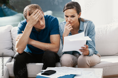 Fotografía Stressed married couple looking frustrated, having no money to pay off their deb