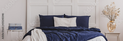 White pillow in the middle of king size bed with blue duvet, copy space on empty Poster Mural XXL