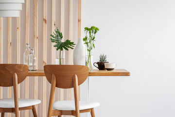 Wall Mural - Green plants in small vases on long wooden dining table in bright interior