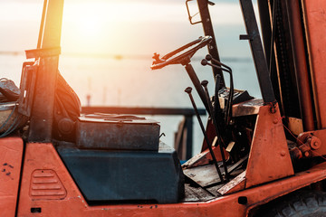 Old Forklift transporting cargo on a road near the sea with sunset time.