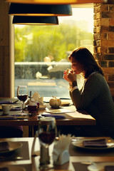 pretty young woman sitting in a cafe with a cup of tea.