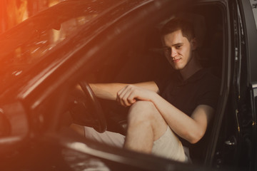 Young man sitting in his car.