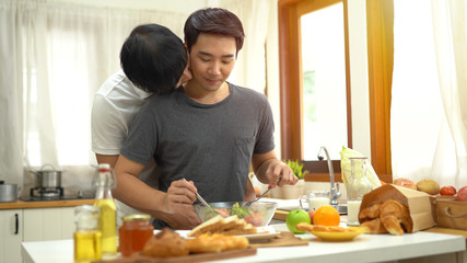 Gay couple homosexual cooking together in the kitchen