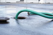 the green thick hose from a sewer pit, pumping sewage or sewage from collector in city. water drainage. Sewer manhole with an open manhole cover and large corrugated suction hoses for waste disposal