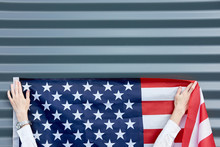Hands Of Woman, Hanging Usa Flag On A Grey Wall, Usa Independence Day Concept