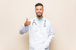 © Asier - Young south-asian doctor man smiling and raising thumb up