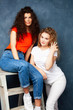 © iordani - young pretty teenage girls friends with blond and brunette curly hair posing cheerful on blue background, lifestyle people concept