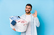 © Asier - Young handsome man doing laundry isolated cheerful and confident showing ok gesture.