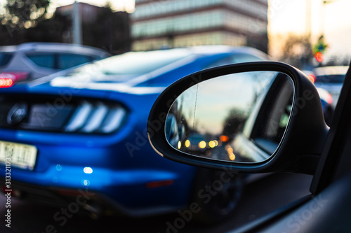 Cuadros en Lienzo Traffic seen thru a car mirror and a Mustang in the background at sunset in Buch