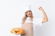 © luismolinero - Teenager girl in chef uniform. Female baker holding a table with several breads over isolated white background celebrating a victory