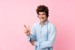 Young caucasian man over isolated pink background pointing side