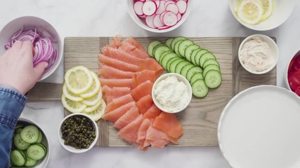 Canvas Print - Flat lay. Step by step. Assembling bagel brunch board with smoked salmon and fresh vegetables.