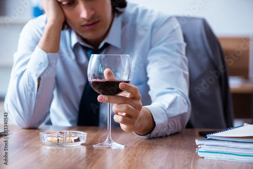 Fotomural Male employee drinking alcohol and smoking cigarettes at workpla