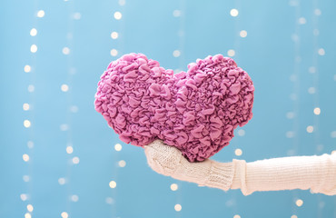 Canvas Print - Young woman holding a big Valentine's day heart on a shiny light blue background