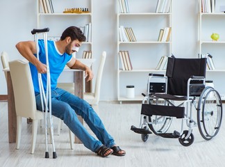 Wall Mural - Young man recovering after surgery at home with crutches and a w