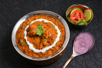 Wall Mural - Butter chicken, Murgh Makhani curry  hot and spicy gravy dish on dark black background in Punjab, Hyderabad Kashmir North India. Top view of popular Indian curries non veg food. 