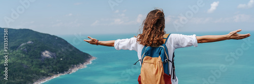 Fotomural Girl relaxing on tropical hill top with arms open felling freedom witn beautiful ocean view from top
