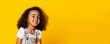 © Prostock-studio - Cute little black girl sincerely laughing over yellow background, long panorama
