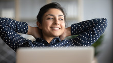 Happy Satisfied Indian Woman Relax With Laptop Looking Away Dreaming