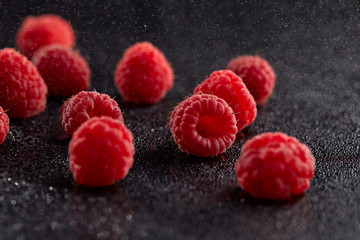 Wall Mural - Fresh raspberries in chaotic order on a dark background with water droplets and shadows.