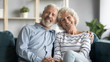 © fizkes - 60s loving couple sitting in living room posing looking at camera