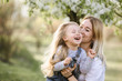young mother with adorable daughter in park with blossom tree