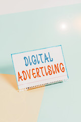 Text sign showing Digital Advertising. Business photo showcasing marketing of products or services using internet Paper placed tilted above buffer wire on soft pastel multi colours backdrop