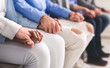 © Prostock-studio - Group of people holding hands, sitting in row