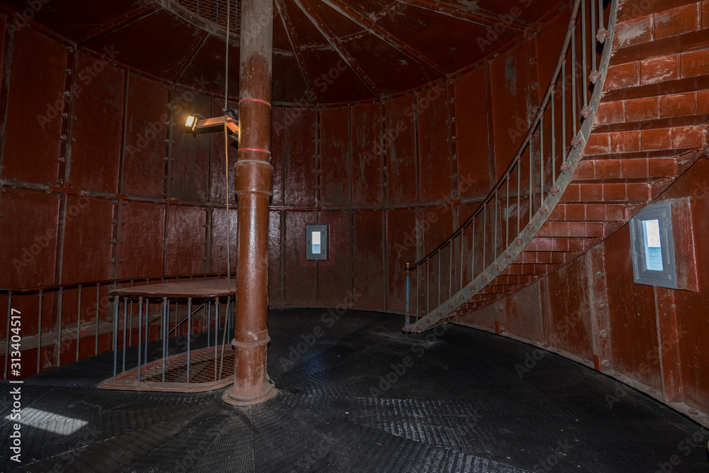 Old lighthouse on the inside. Red iron spiral stairs, round window and ...