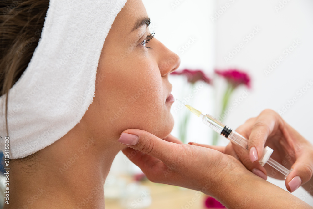 Powiększenie ust kwasem hialuronowym. Twarz kobiety podczas zabiegu modelowania ust. Kosmetolog wstrzykuje wypełniacz, medycyna estetyczna.  - obrazy, fototapety, plakaty 